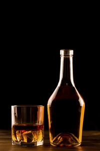 杯加冰和木制的桌子上一瓶威士忌。科涅克白兰地白兰地