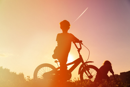 在日落时的小男孩骑自行车