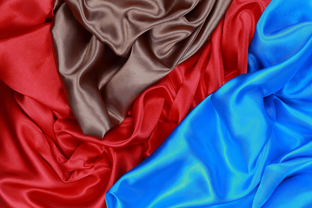蓝色和棕色和红色丝缎布的波浪褶皱纹理坝