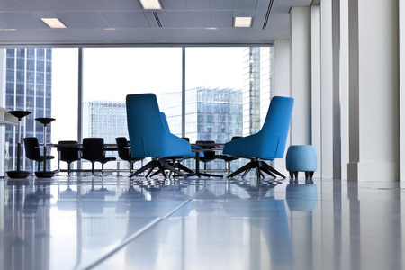 在宽敞明亮的现代蓝色旋涡的办公椅打开房间有大窗户和模糊的建筑物外面