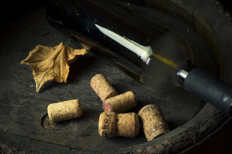 红葡萄酒瓶和木制桶，背景上的葡萄园