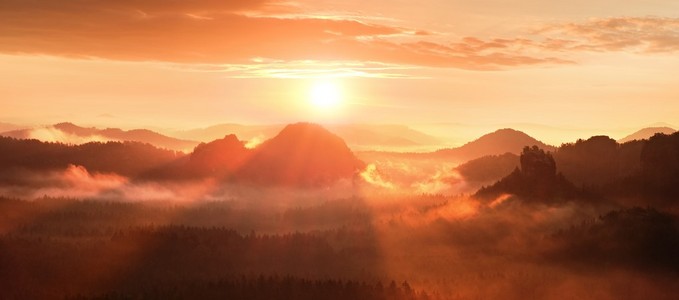 在美丽的山丘的红雾破晓。山山峰都突出来了从雾背景，红色和橙色雾阳光下面