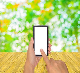 男性手拿着现代触摸屏手机和模糊图像的抽象波克树绿色背景。