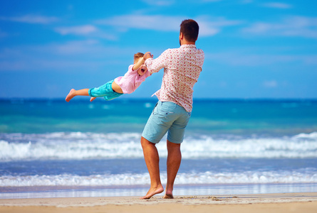 快乐兴奋的父亲和儿子玩在夏天的海滩，享受生活