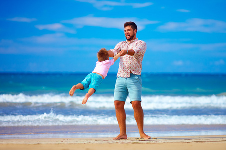 快乐兴奋的父亲和儿子玩在夏天的海滩，享受生活