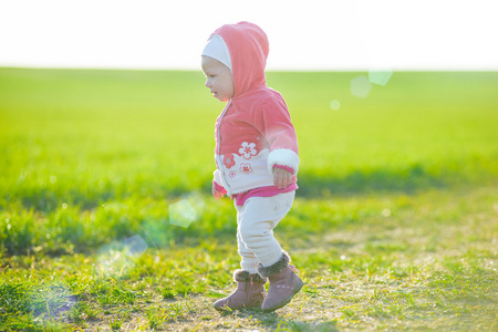 快乐的小女孩走在草地上，看着太阳