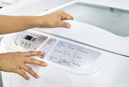 手指按按钮开始对白色洗衣机
