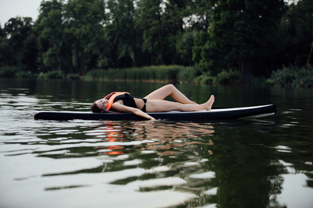 女人躺在水面上的桨板