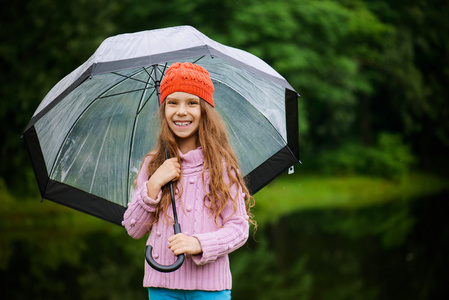 穿着粉红色毛衣撑着伞的漂亮小女孩