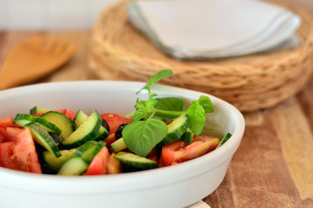 健康的蔬菜色拉，配黄瓜，西红柿上白色的瓷器碗