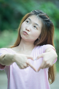 亚洲幸福的年轻女人制作心标志与手