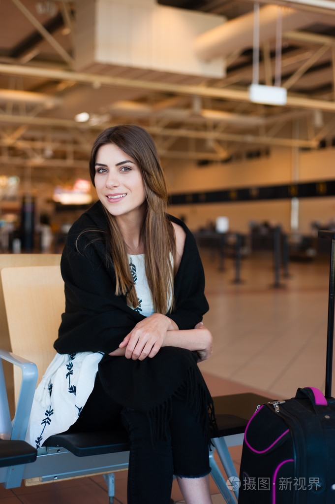 在大门口等候在码头等待她的航班机场年轻女乘客