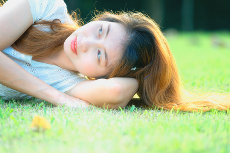 亚洲美丽的年轻女子躺在绿色的草地上