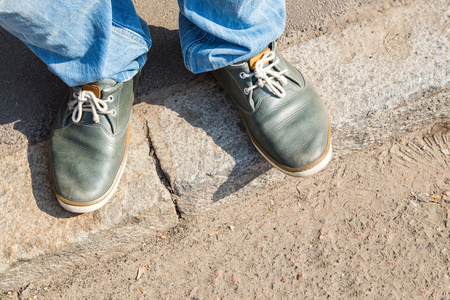 年轻人脚在鹅卵石的道路上的运动鞋