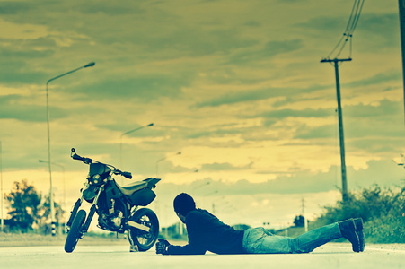 骑自行车的人放松与摩托车路上躺在日落
