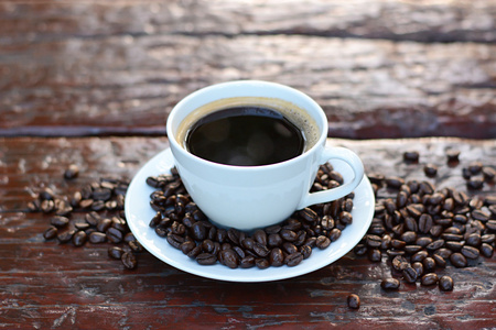 黑咖啡的咖啡豆的旧木桌上的杯子