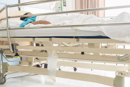 透明塑料尿袋挂在床上的女病人照片