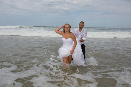 愉快的新娘和新郎运行在一个美丽的沙滩上