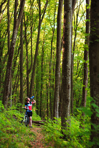 女游客和自行车享受木材查看从路径