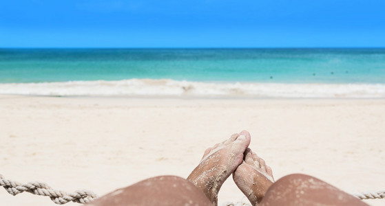 脚在沙滩上与广阔的海地平线，集中在脚上
