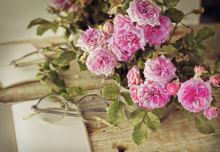 戴着眼镜木制的桌子上的粉红玫瑰