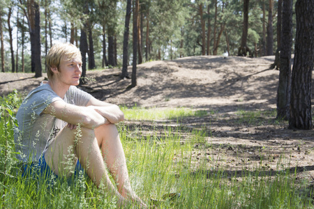 夏天, 松树林坐在草地上的金发碧眼的男人