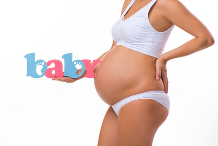 怀孕。做了母亲。蓝色和粉红色的词婴儿附近的怀孕的肚子。双胞胎，男孩还是女孩