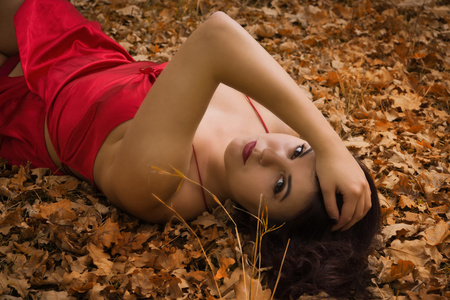 在秋天的树林中的一件红色连衣裙的女孩