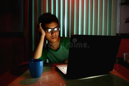 戴着眼镜在笔记本电脑前无聊的年轻人