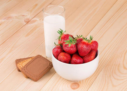 新鲜草莓和牛奶放在木头上的玻璃杯里。
