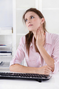 坐在办公桌前的年轻女子，颈部疼痛或肿胀