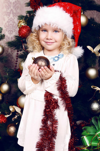 可爱的小女孩戴着圣诞帽装饰圣诞树