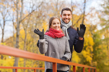 一对微笑的情侣在秋天公园的桥上拥抱