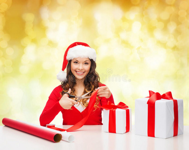 戴圣诞老人帽的微笑女子包装礼品盒