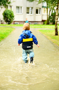 雨后在水坑里奔跑的可爱男孩