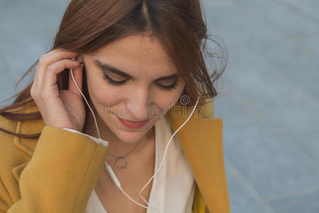 红发女孩在城市街道上听音乐