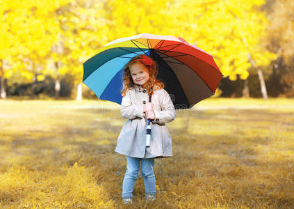 秋日阳刚可爱的孩子撑着五颜六色的伞