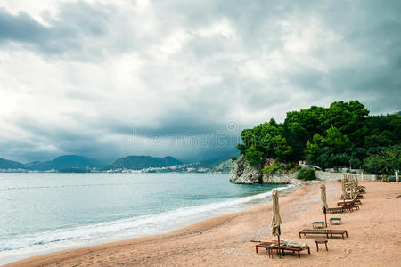 豪华海滩度假村，配有日光浴床和雨伞，天空多雨