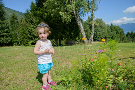 一个漂亮的小女孩在花园里玩花