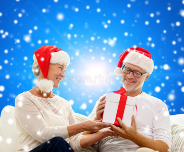 快乐的老夫妇戴着圣诞帽，带着礼盒