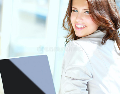 年轻微笑的女人坐在笔记本电脑前