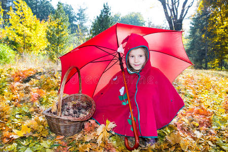 秋天，可爱的小女孩在树叶里玩伞