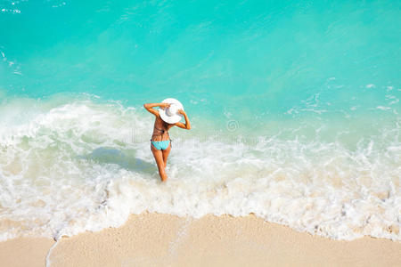 海滩上背着白帽子的年轻女人