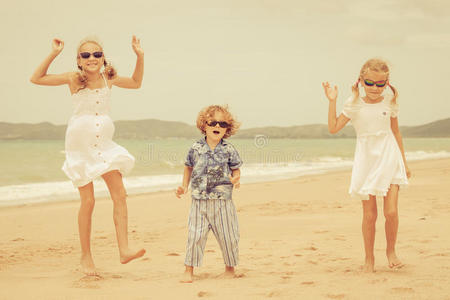 三个快乐的孩子在海滩上跳舞