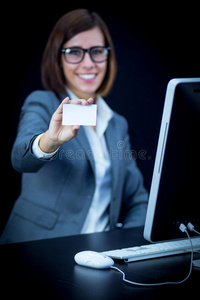 女人在电脑前工作并出示卡片
