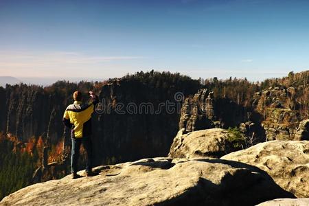 这名男子正在岩石帝国公园的山顶上用智能手机拍照，看着秋天的薄雾谷。