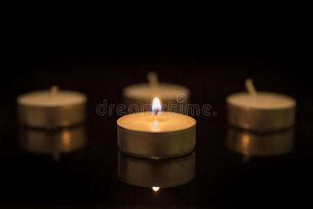 四支茶蜡烛，反光在黑色上