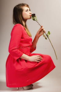 时尚女性少女穿着红色长袍和干玫瑰。