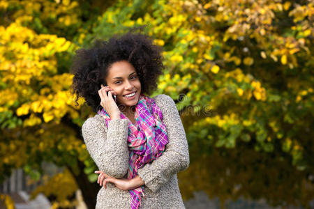 微笑的年轻女子在户外用手机打电话