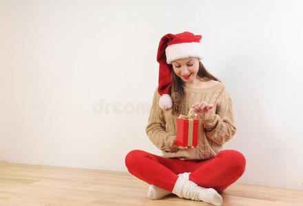 可爱的年轻女子戴着圣诞帽，手里拿着礼物盒
